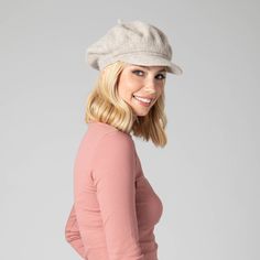 a woman wearing a hat and smiling at the camera with her hands on her hips