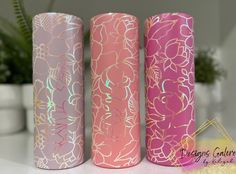 three pink and purple vases sitting next to each other on a white counter top