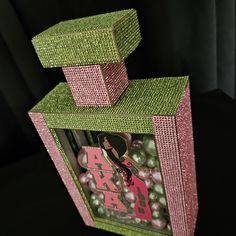 a pink and green box with pearls in it on a black tableclothed surface