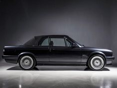 an image of a black car parked in the dark room with its hood up and windows down