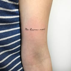 a woman's arm with the word be here now tattooed on her left arm