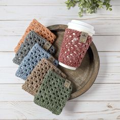 four crocheted coffee cups sitting on top of a wooden tray next to each other