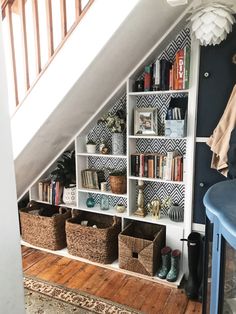 a bookshelf under the stairs with baskets and other items on shelves underneath it