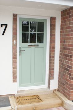 the front door is painted pale blue and has a welcome mat on the sidewalk next to it