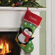 a christmas stocking with a penguin on it hanging from a mantel above a fireplace