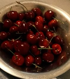 a metal bowl filled with lots of cherries