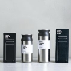 three travel mugs sitting next to each other in front of a box on a table