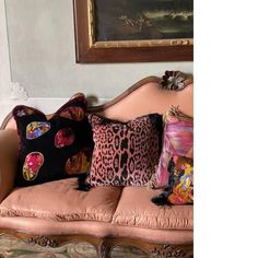 a couch with several pillows on it in front of a painting and framed art piece