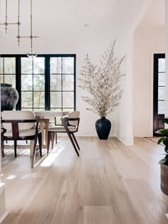 a dining room table with chairs and a vase on the floor in front of it