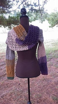 a mannequin wearing a crocheted scarf on top of a wooden stand