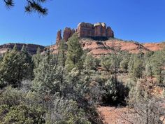 the mountains are covered with trees and bushes in front of some tall rock formations on a sunny day