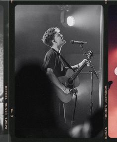 a black and white photo of a man singing into a microphone while holding a guitar