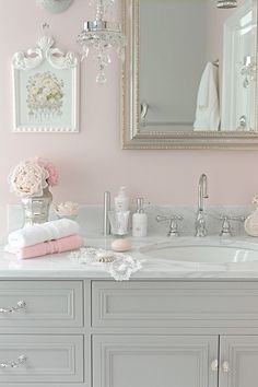 a bathroom with pink walls and white vanity, chandelier and mirror above the sink