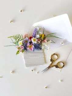 a pair of scissors sitting on top of a piece of paper next to some flowers