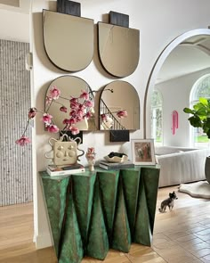 a living room filled with furniture and mirrors on the wall next to a cat walking in front of it