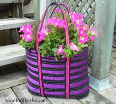 a purple and black striped bag with pink flowers in it on a wooden deck next to a bench