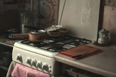 a stove top oven sitting inside of a kitchen next to a counter with pots and pans on it