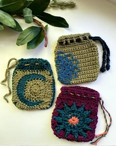 three crocheted purses sitting next to each other on a white counter top