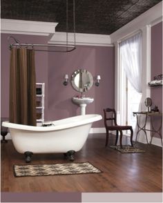 a bath tub sitting on top of a hard wood floor next to a white sink