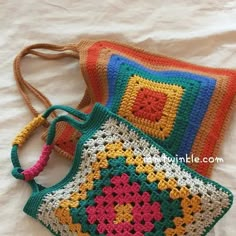 two crocheted purses sitting next to each other on a white sheet with the handles down