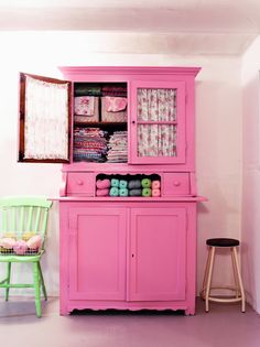 a pink hutch sitting next to a green chair