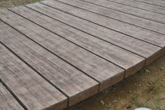 a close up of a wooden deck in the grass with an object on the ground next to it