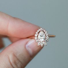 a woman's hand holding an engagement ring with a diamond center stone on it