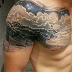 a man's chest with a lighthouse and clouds tattoo on his left side shoulder