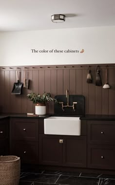 a kitchen with dark wood cabinets and white sink, black countertops and gold faucets