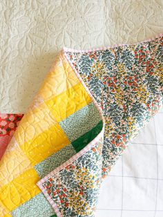 two quilts laying next to each other on top of a white bed coverlet