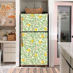 a refrigerator covered in yellow lemons next to a wallpapered kitchen with white cabinets