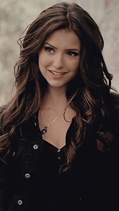 a woman with long brown hair smiling at the camera