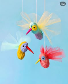 three colorful birds hanging from strings in the sky