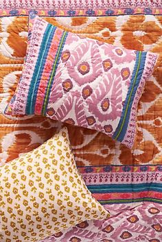 two colorful pillows sitting on top of a bed