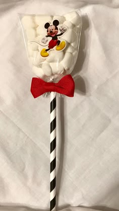 a mickey mouse lollipop on a black and white striped stick with a red bow