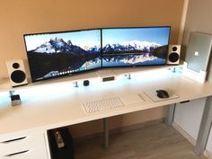 two computer monitors sitting on top of a white desk