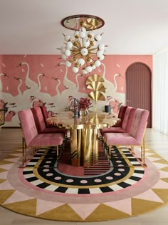 a pink and gold dining room with flamingos on the wall, chandelier and chairs