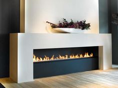 a modern fireplace with fire burning in it's side and flowers on the mantle