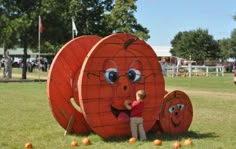 a young boy standing in front of a giant pumpkin shaped object with two faces on it