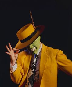 a man in a yellow suit and top hat with his hands out to the side