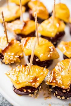 mini pineapples with toothpicks and sesame seeds on a white platter