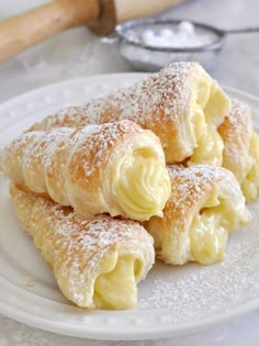 three pastries on a plate with powdered sugar and a rolling pin in the background