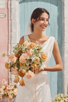 a woman holding a bouquet of flowers in front of a blue door with pink and yellow flowers