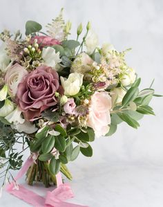 a bouquet of flowers with pink ribbon on white table cloth and marble background, closeup