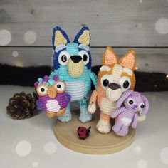 three small crocheted animals standing next to each other on a white surface with snowflakes