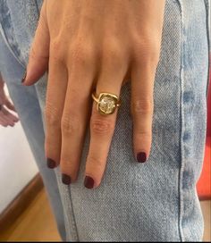 a woman's hand wearing a gold ring with a diamond in the middle and on her finger