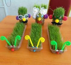 some fake grass plants with googly eyes and flowers in them on a wooden table