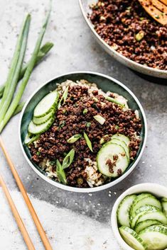 two bowls filled with meat and cucumbers next to chopsticks