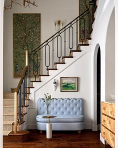 a blue couch sitting under a stair case in a living room next to a wooden floor