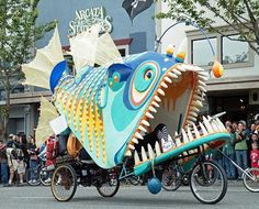 an elaborately decorated fish is riding on a bike